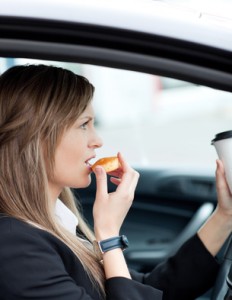 Attractive businesswoman eating and holding a drinking cup while
